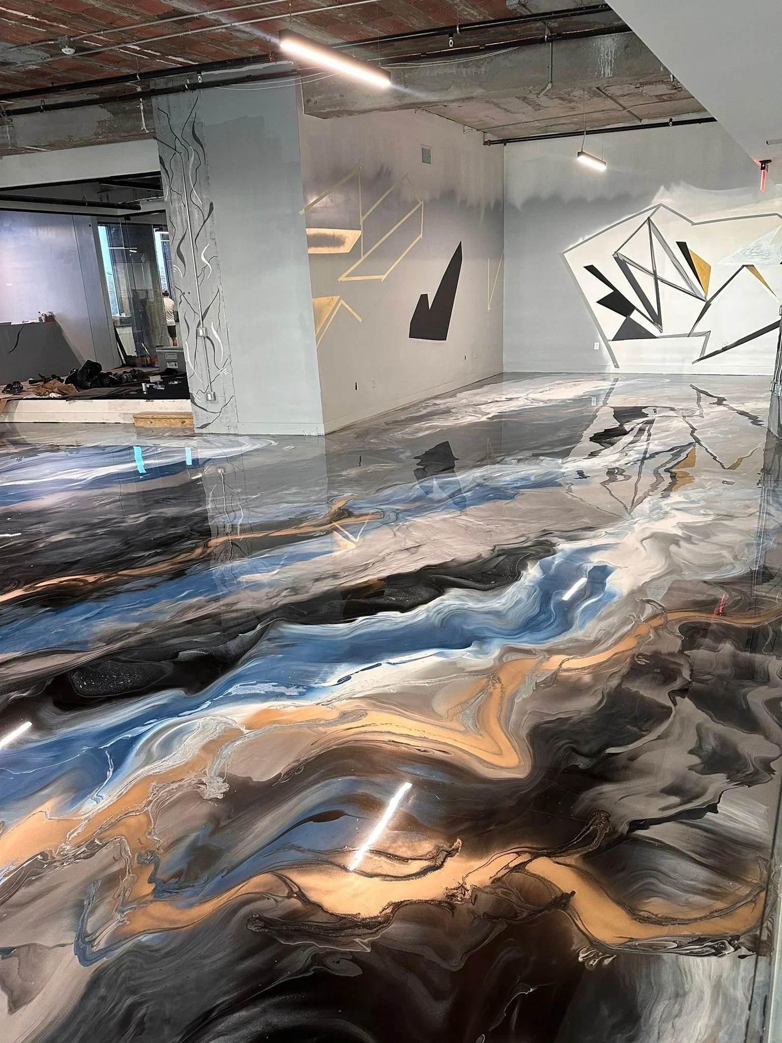Metallic epoxy resin floor with blue, gold, and charcoal swirl patterns in commercial space