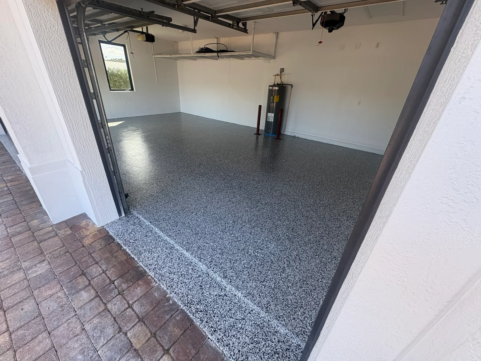 Gray speckled epoxy garage floor with glossy finish and clean entry transition