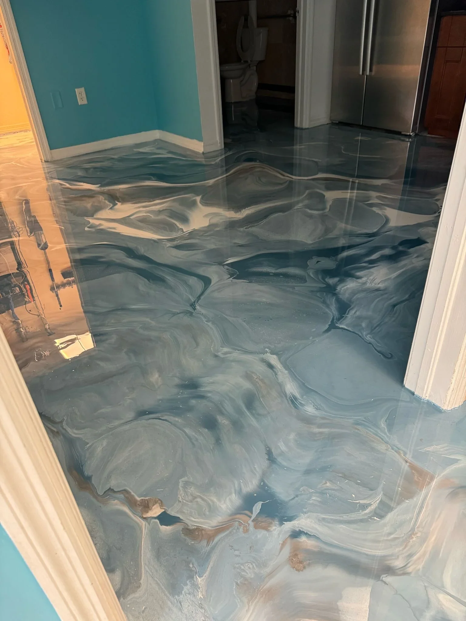 Metallic epoxy floor with gray and teal swirled pattern, high-gloss finish in kitchen