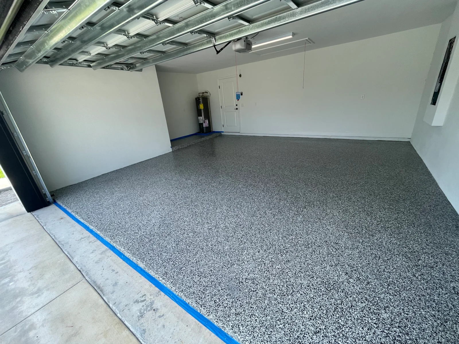 Finished garage floor with gray speckled epoxy coating, white walls, and metal ceiling framing
