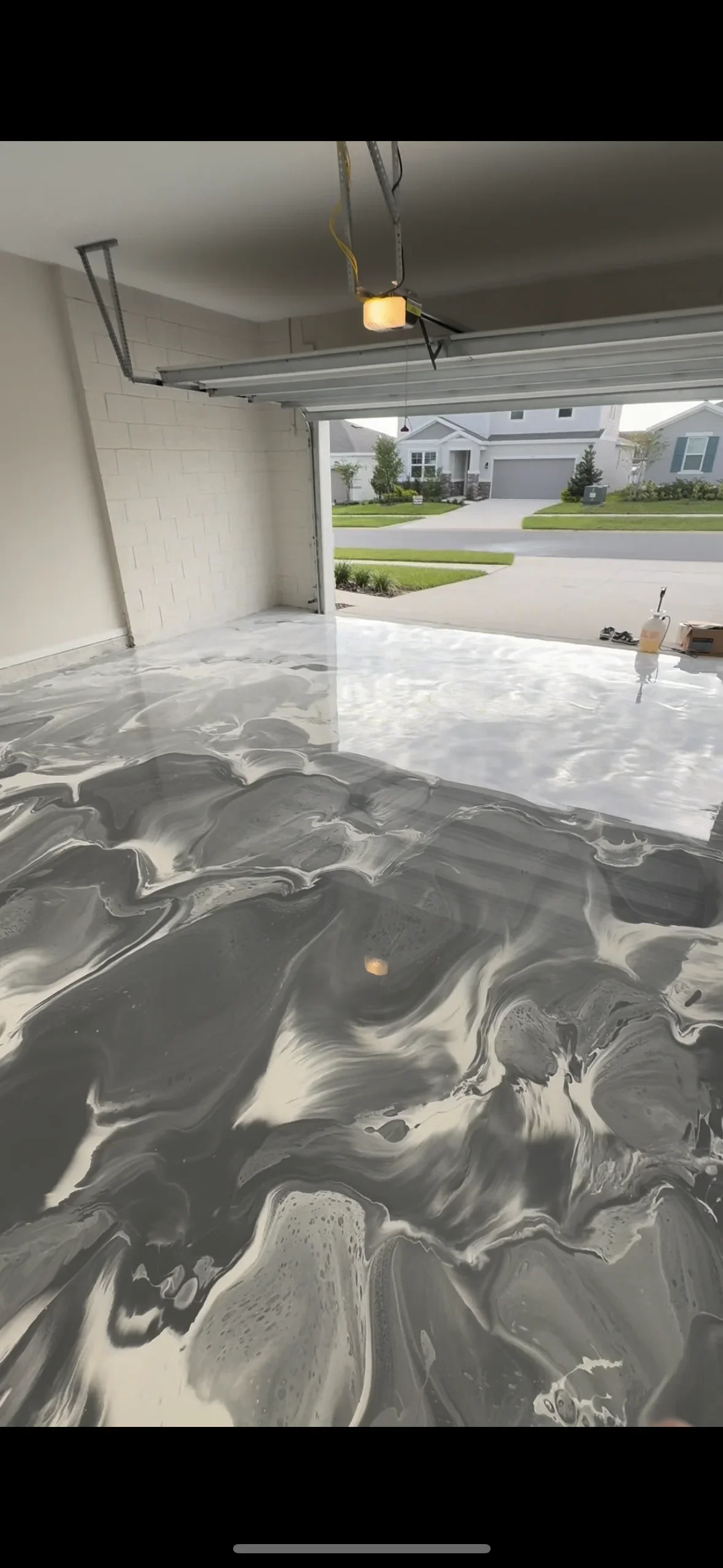 Gray and white marbled epoxy garage floor with glossy finish and metallic swirls