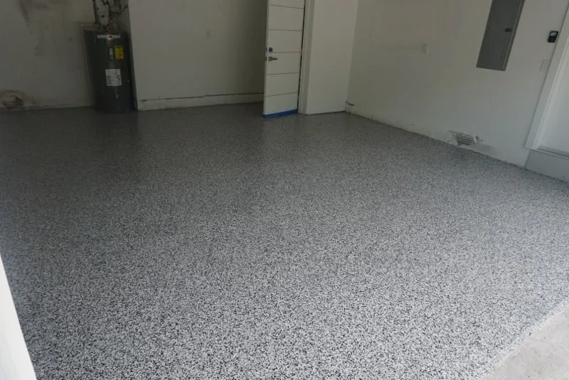 Gray speckled epoxy-coated garage floor with white walls and utility equipment
