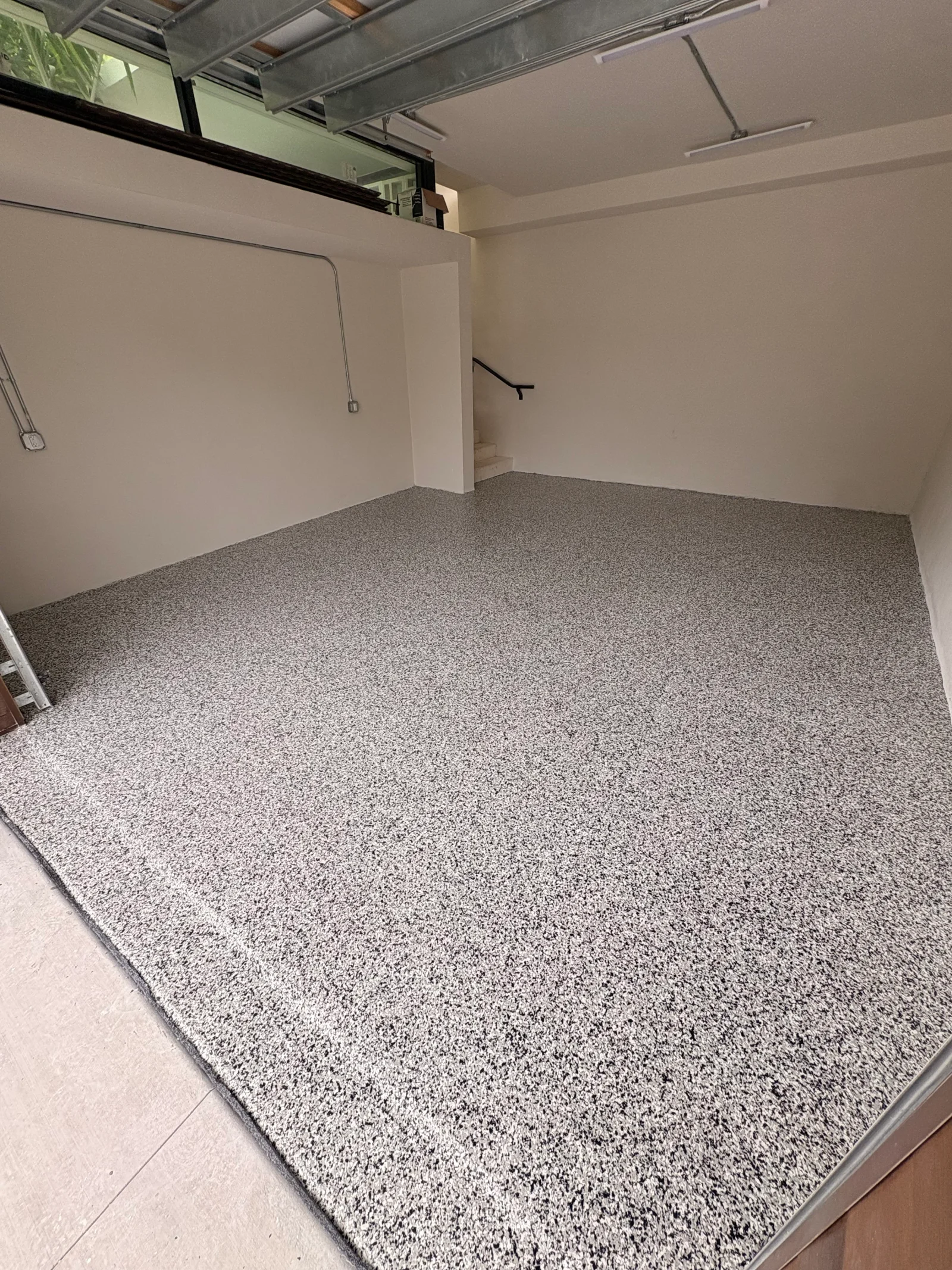 Light gray speckled epoxy floor coating in garage with finished edges and uniform coverage