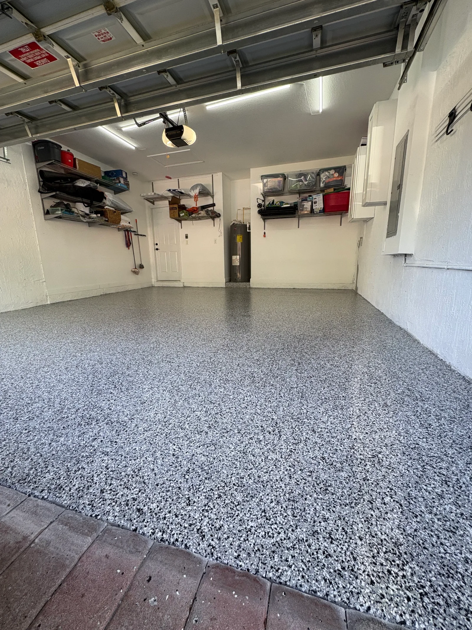 Gray speckled epoxy garage floor with white walls and metal shelving