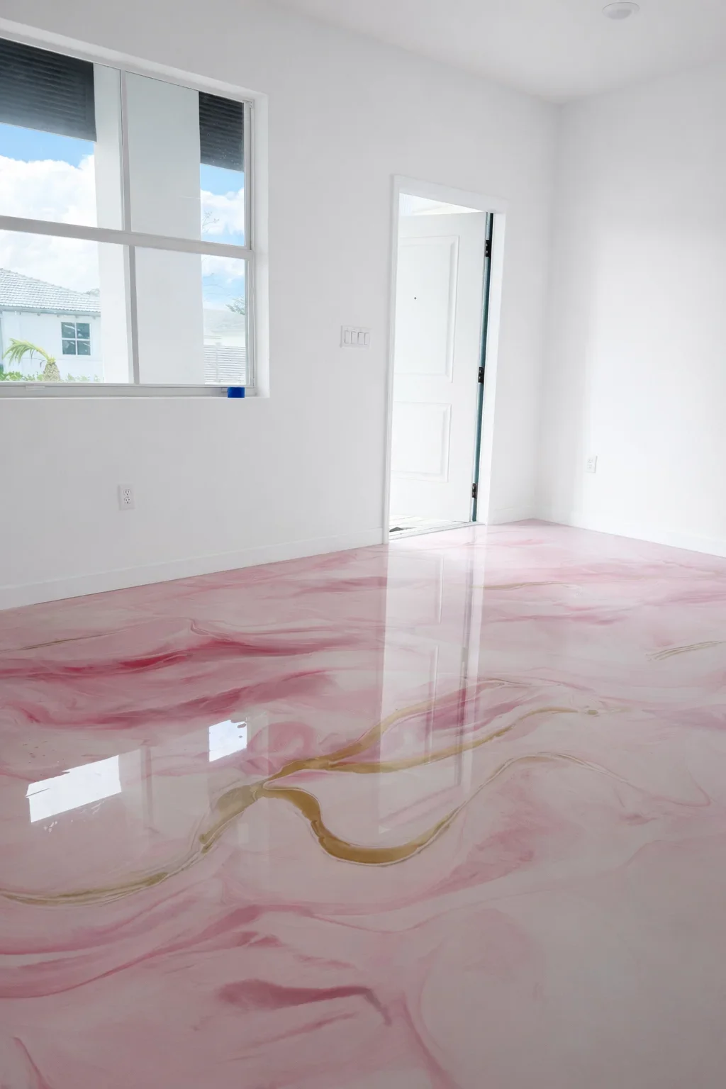 Pink and gold swirled epoxy resin floor with glossy finish in bright room